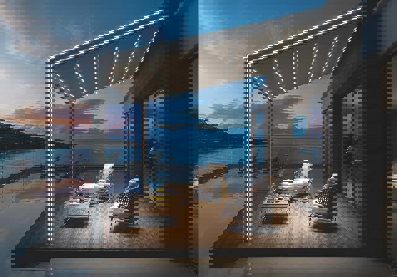 Moderna pergola z integrirano LED osvetlitvijo na terasi ob morju v večernem ambientu, z elegantnim pohištvom za sprostitev.