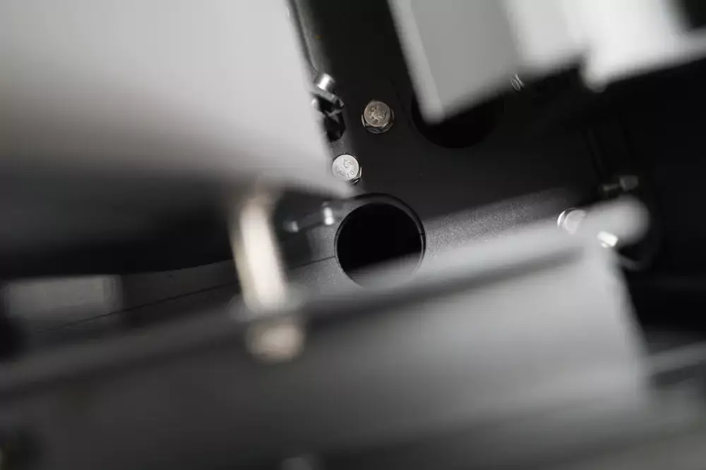 Pogled od blizu na notranji del pergole z vidnim integriranim sistemom za odvodnjavanje, ki prikazuje cev in vijake konstrukcije.